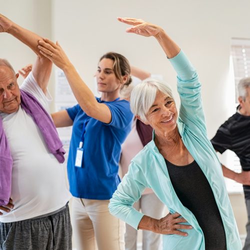 Senior people stretching with trainer at retirement community